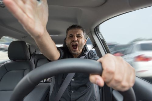 Wide angle look inside in the car of actually driving young male with hands in foreground concept