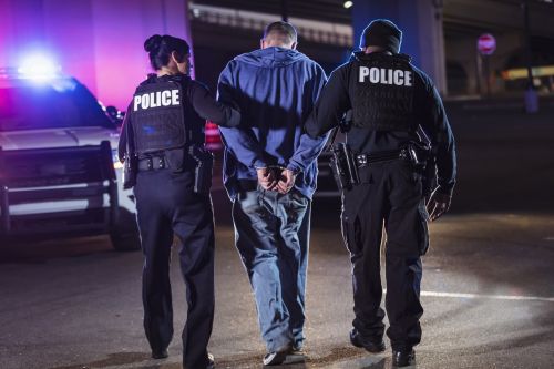 Handcuffed suspect being arrested by police at night