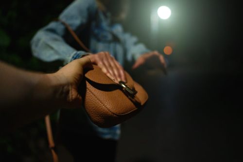 Thief snatches bag from woman on the night street.