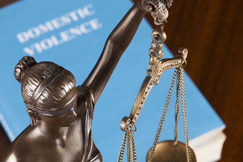 A mock law book on domestic violence next to Lady Justice.
