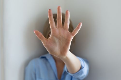 woman holding up her hand to block her face