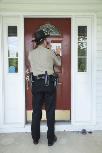 officer posting a notice on a front door