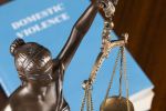 A mock law book on domestic violence next to Lady Justice.